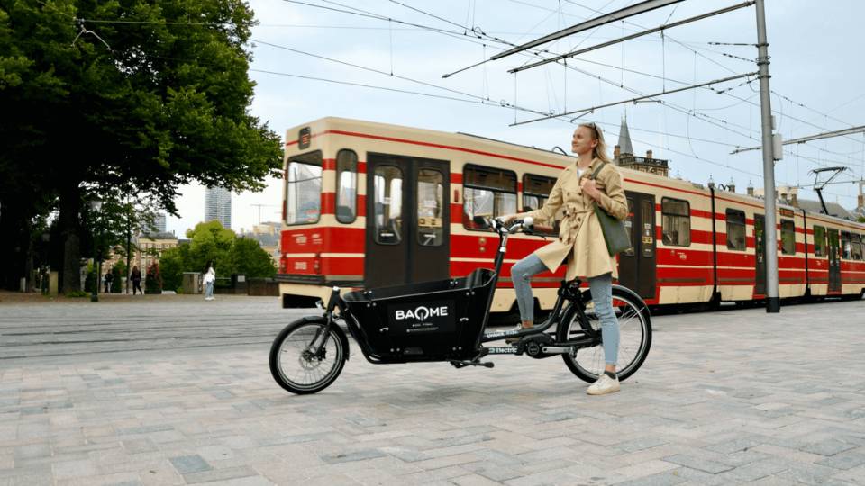 Women on bakfiets of Baqme next to tram in city